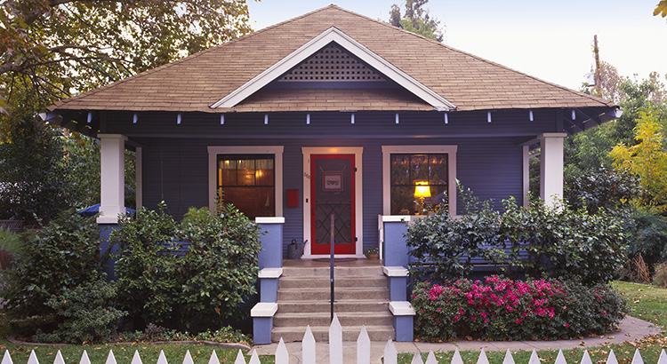 Charming small bungalow with a picket fence, representing cozy and affordable housing options.