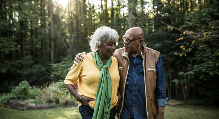 Happy senior couple walking and embracing in a serene garden, symbolizing the lifestyle and financial freedom of well-planned retirement.