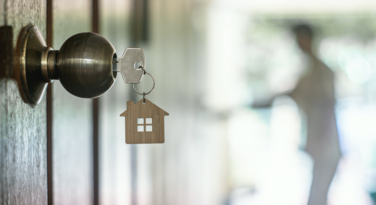 Close-up of a key in a door lock with a house-shaped keychain, symbolizing the importance of pre-approval in the home buying process.