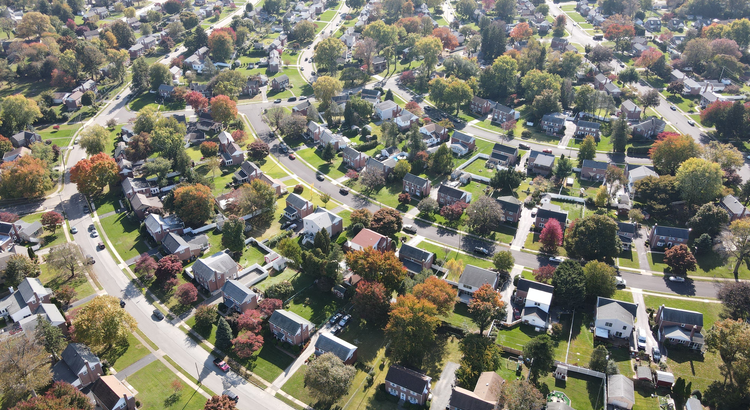 Aerial view of a suburban neighborhood with winding streets and colorful trees, symbolizing stable and thriving housing markets.