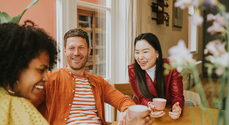 Group of friends laughing and enjoying coffee together, symbolizing the social benefits of owning your first home.