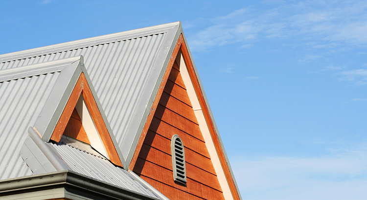 Close-up of a house's gable roof with blue sky in the background, symbolizing considerations for homebuyers regarding climate risks.