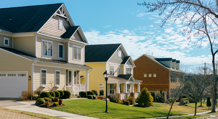Row of modern suburban homes with well-kept lawns under a clear blue sky, symbolizing the latest expert forecasts for home prices.