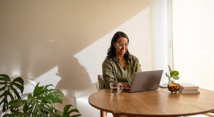 Young woman working on a laptop at a table, symbolizing affordable homeownership strategies for Gen Z.