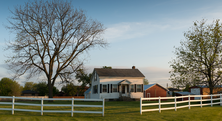 Small house with a white fence and large yard, symbolizing accessory dwelling units (ADUs) and their benefits.