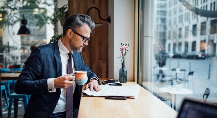 Businessman reading a housing market analysis report with a cup of coffee.