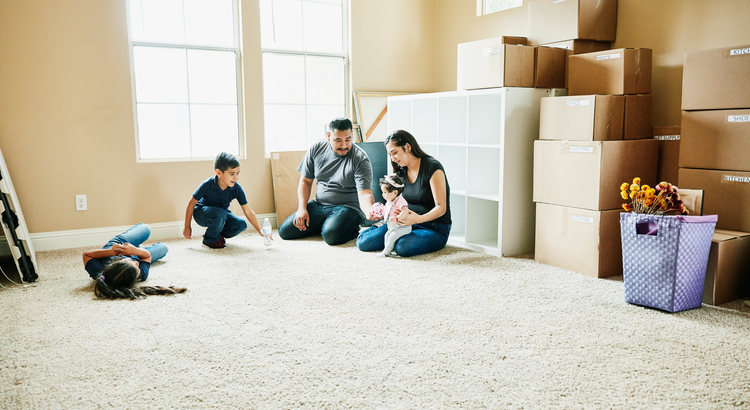 Family sitting on the floor surrounded by moving boxes, symbolizing the excitement of moving into a new home.