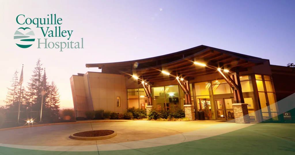 Exterior view of Coquille Valley Hospital at sunset, with the hospital logo.