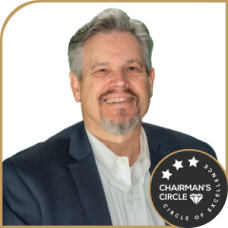 Mark Irwin smiling in a suit, wearing a Chairman’s Circle badge.