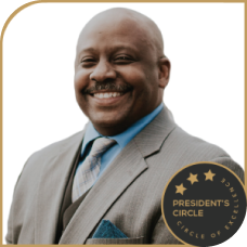 Maurice Grant smiling in a suit, wearing a President’s Circle badge.